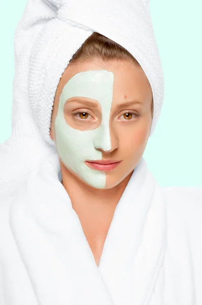 Beauty Spa. Woman applying clay mask on face. Pastel background — Stock Photo, Image