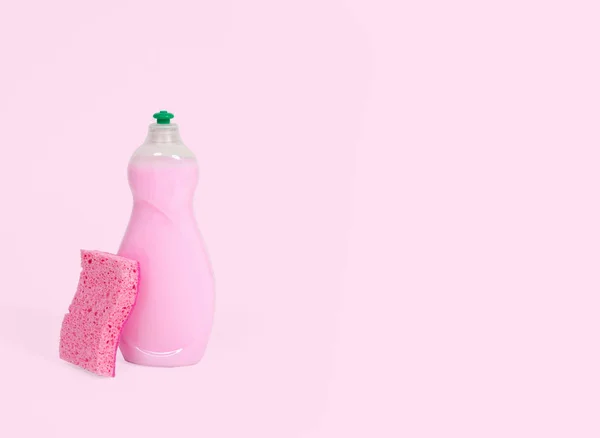 Liquide vaisselle avec éponges sur couleur rose pastel — Photo