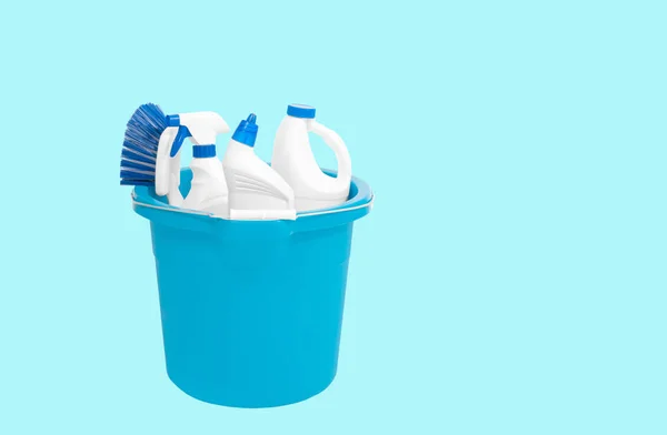 Cleaning supplies in blue bucket on pastel green background — Stock Photo, Image