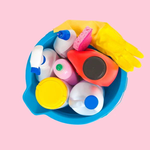 Artículos de limpieza en cubo azul sobre fondo rosa pastel — Foto de Stock