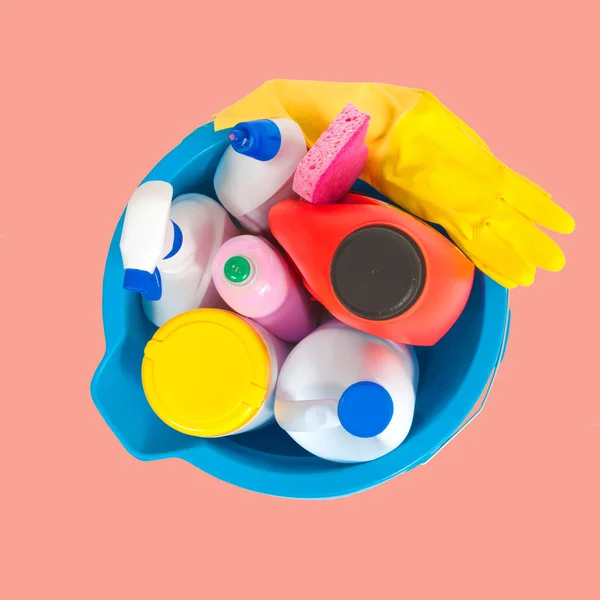 Artículos de limpieza en cubo azul sobre fondo rosa pastel — Foto de Stock