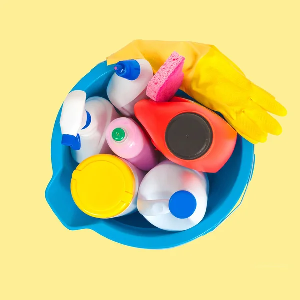 Cleaning supplies in blue bucket on pastel yellow background — Stock Photo, Image