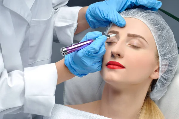 Microblading. Cosmetólogo haciendo maquillaje permanente. Mujer atractiva recibiendo cuidado facial y cejas de tatuaje —  Fotos de Stock