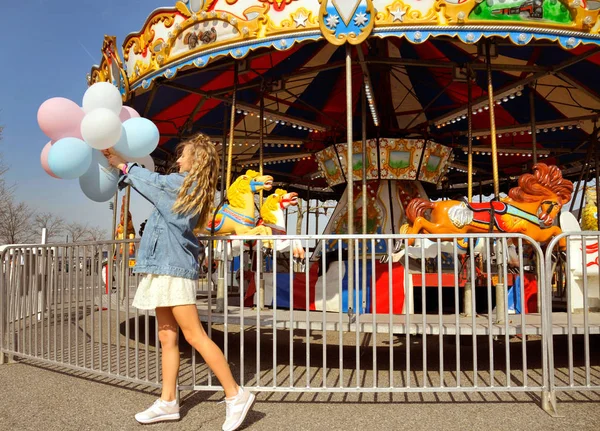 Piękna młoda kobieta z balonami w parku rozrywki — Zdjęcie stockowe