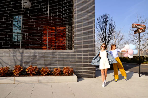 Chicas urbanas de moda con atuendo de moda con globos caminando en la calle de la ciudad de Nueva York . — Foto de Stock