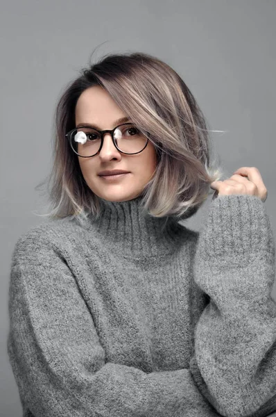 Модна жінка в окулярах в стильному сірому светрі — стокове фото