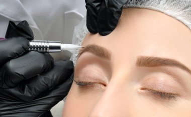 Microblading. Cosmetologist making permanent makeup. Attractive woman getting facial care and tattoo eyebrows clipart