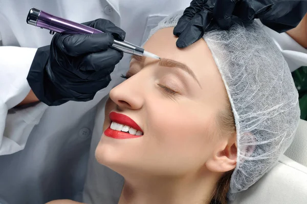 Microblading. Cosmetologist fazendo maquiagem permanente. Mulher atraente recebendo cuidados faciais e sobrancelhas de tatuagem — Fotografia de Stock