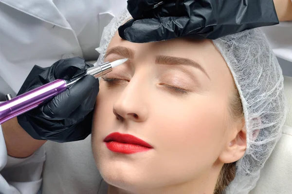 Microblading. Cosmetólogo haciendo maquillaje permanente. Mujer atractiva recibiendo cuidado facial y cejas de tatuaje —  Fotos de Stock