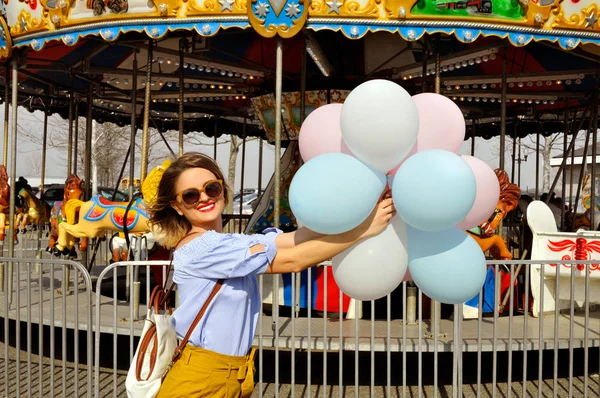 Beautiful young woman with balloons in the amusement park — Stock Photo, Image