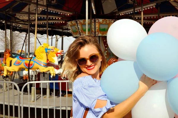 Mulher bonita com balões no parque de diversões — Fotografia de Stock