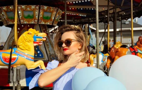 Красива молода жінка з повітряними кулями в парку розваг — стокове фото