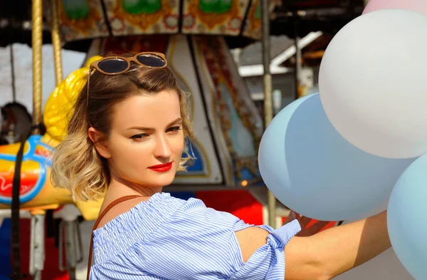 Hermosa joven con globos en el parque de atracciones — Foto de Stock
