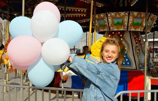 Beautiful young woman with balloons in the amusement park — Stock Photo, Image