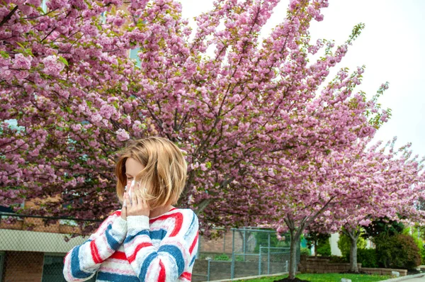 Весенняя аллергия. Женщина, дующая рядом с весенним деревом в цвету . — стоковое фото