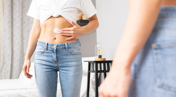 Woman applying moisturizer cream lotion on belly