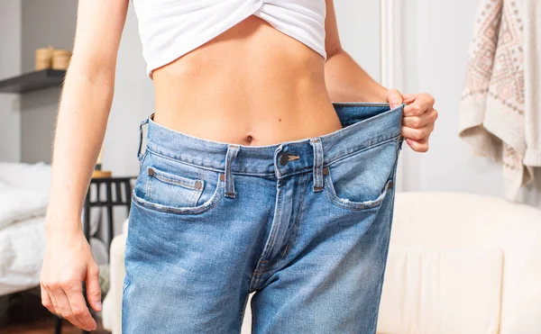 Chica delgada en pantalones vaqueros de gran tamaño después de una dieta exitosa . — Foto de Stock