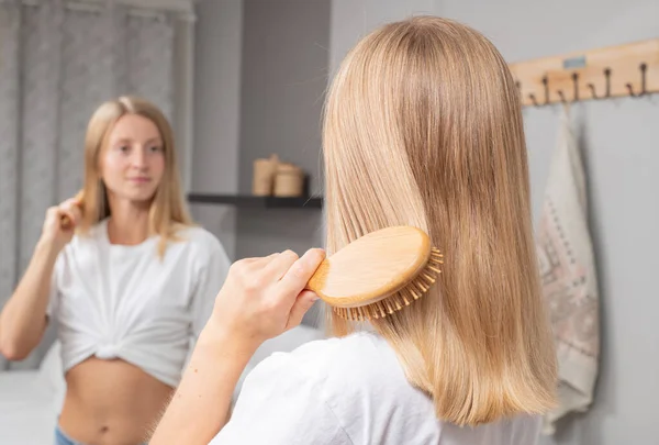 Schöne Frau beim Haareputzen zu Hause im Spiegel — Stockfoto