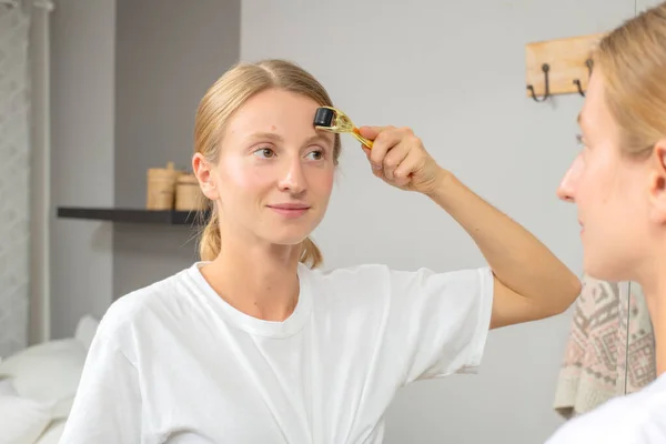 Dermaroller. Vrouw maakt procedure op gezicht met meso roller in huis — Stockfoto