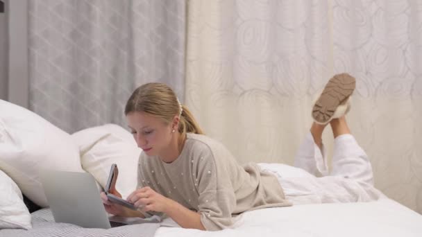 아름다운 침대에서 노트북으로 타자를 있습니다 신용카드로 온라인 쇼핑을 여성들 — 비디오