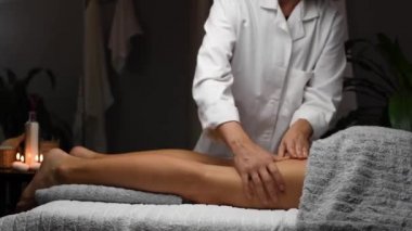 Güzel genç bir kadın spa merkezinde selülit karşıtı masaj yaptırıyor. Masör masaj masasında profesyonel bacak masajı yapıyor..