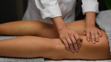 Güzel genç bir kadın spa merkezinde selülit karşıtı masaj yaptırıyor. Masör masaj masasında profesyonel bacak masajı yapıyor..