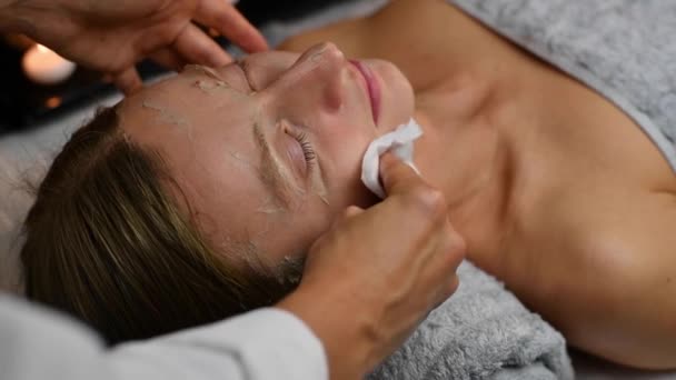 Kozmetológus eltávolítja agyag maszk női arc, nő kap kozmetikai kezelések szépségszalonban.