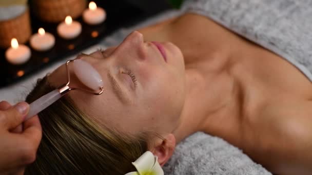 Cosmetologue Faisant Massage Professionnel Visage Aide Rouleau Jade Femme Recevant — Video