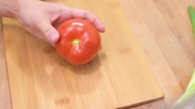 Dişi eller domatesi keser. Mutfak bıçağı kullanan kadın tahtada taze domates dilimliyor.