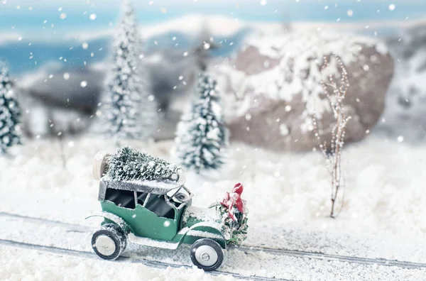 Мініатюрний класичний автомобіль, що перевозить ялинку на засніженій дорозі взимку — стокове фото
