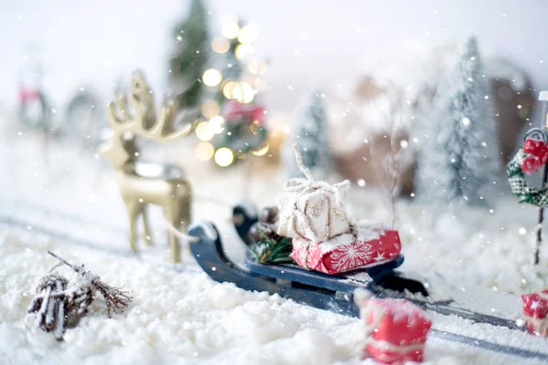 Miniatur-Schlitten voller Geschenke auf schneebedecktem Hintergrund — Stockfoto