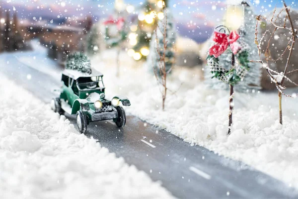Miniatur-Oldtimer trägt einen Weihnachtsbaum auf Winterzauber Hintergrund — Stockfoto