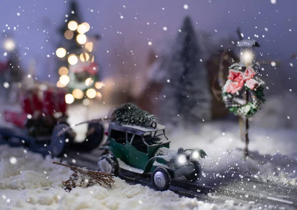 Мініатюрний класичний автомобіль, що перевозить ялинку та подарунки на засніженій дорозі на зимовому тлі — стокове фото