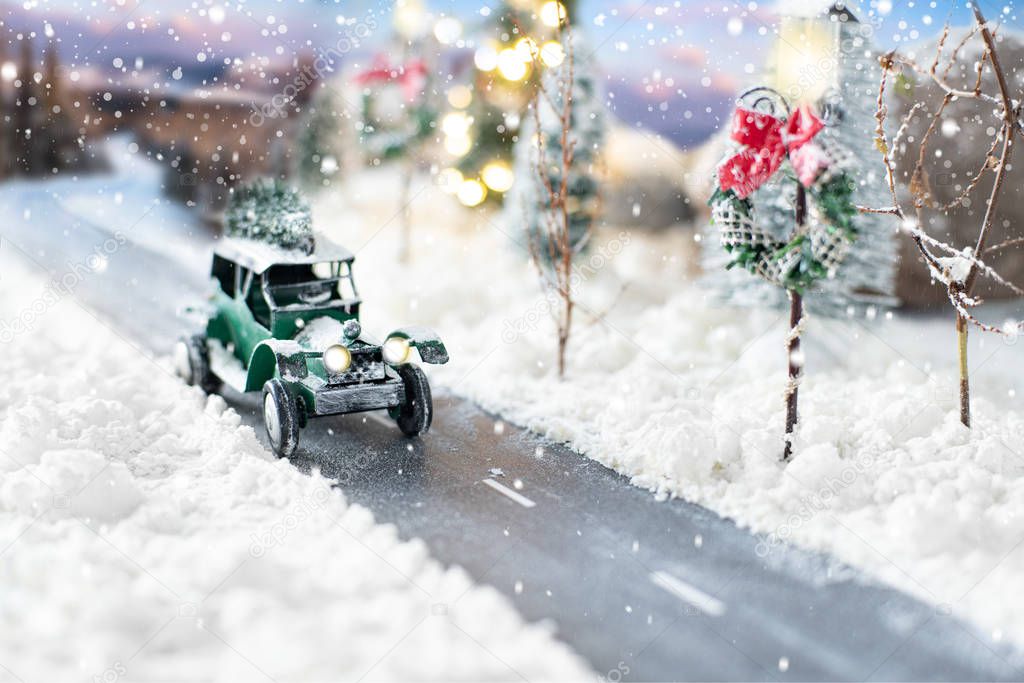 Miniature classic car carrying a christmas tree on winter magic background