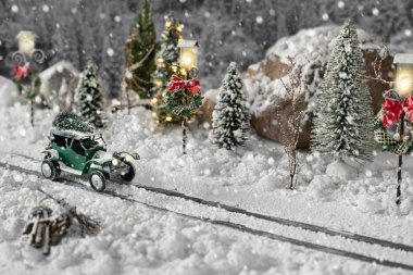 Minyatür klasik araba kışın karlı yolda bir Noel ağacı taşıyor.