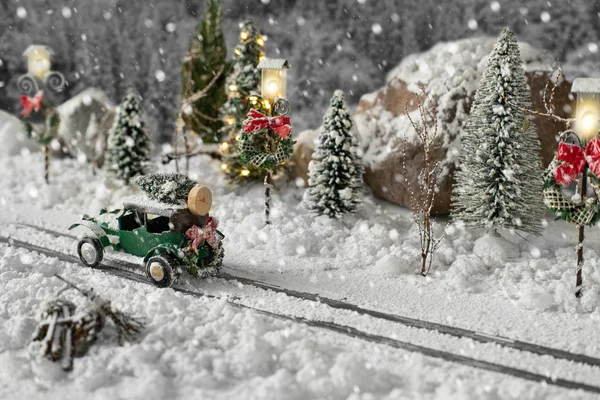 Miniature classic car carrying a christmas tree on snowy road on winter — Stock Photo, Image