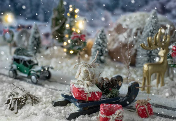 Traîneau chargé de cadeaux et voiture miniature portant un arbre de Noël sur un paysage enneigé — Photo