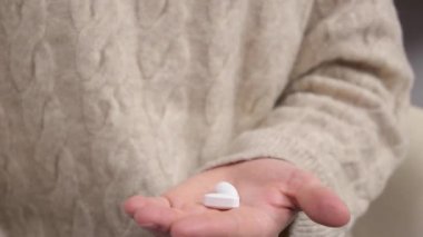 Avucunun içine iki hap alıp haplar ya da vitaminler alan bir kadın.
