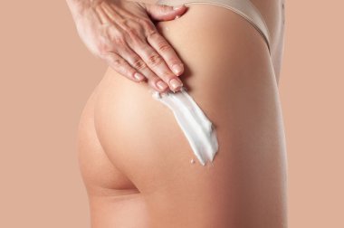 Vücut bakımı. Bacaklarına ve kalçalarına krem süren bir kadın..