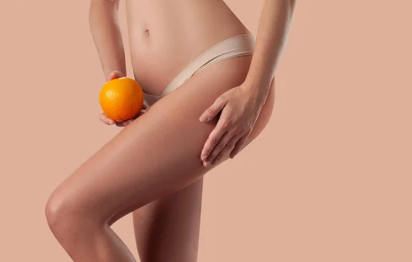 Η αδύνατη γυναίκα κρατάει το πορτοκάλι. Τέλεια γυναικεία ισχία με εσώρουχα w — Φωτογραφία Αρχείου