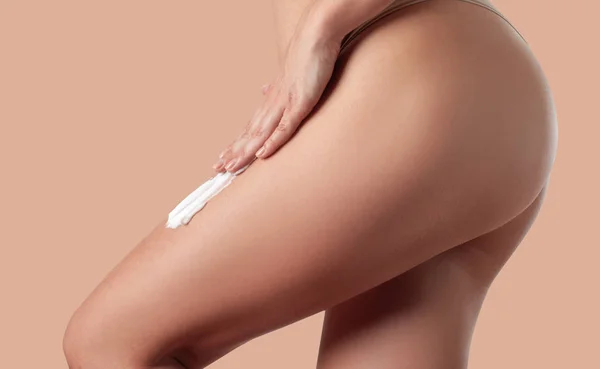 Cura del corpo. Donna che applica crema anticellulite sulle gambe . — Foto Stock