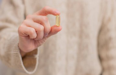 Balık yağı kapsülleri. Kadın Omega 3 'ü elinde tutuyor..