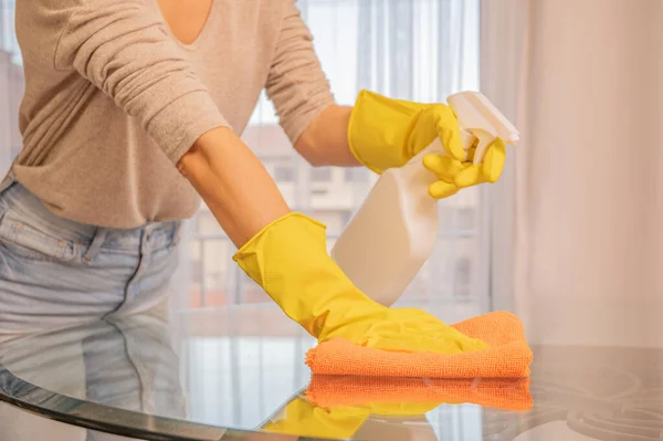 Woman in yellow gloves cleaning glass table. — Stock Photo, Image