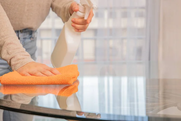 Woman is cleaning glass table with spray. — Stock Photo, Image