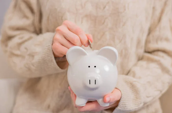 Woman is putting coins into piggy bank. — Stock Photo, Image