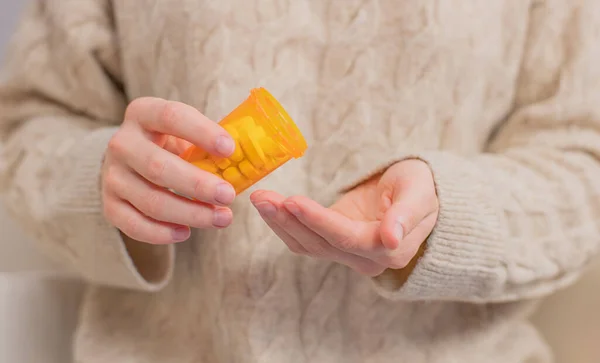 Жінка приймає таблетки вітамінів. Жінка тримає банку таблеток — стокове фото