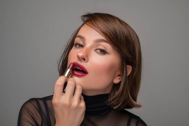 Profesyonel makyajla. Güzel esmer kadın kırmızı ruj sürüyor..