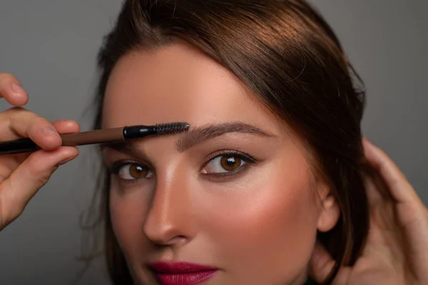 Krásné oči ženy s úžasným make-upem. Dívka aplikuje make-up na obočí — Stock fotografie