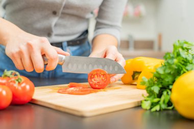Kadın mutfakta domatesleri kesiyor. Salata için taze sebze.