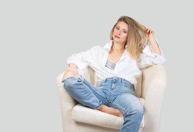 Şık kıyafetler. Stüdyoda kot pantolon ve beyaz gömlek içinde güzel bir kadın.